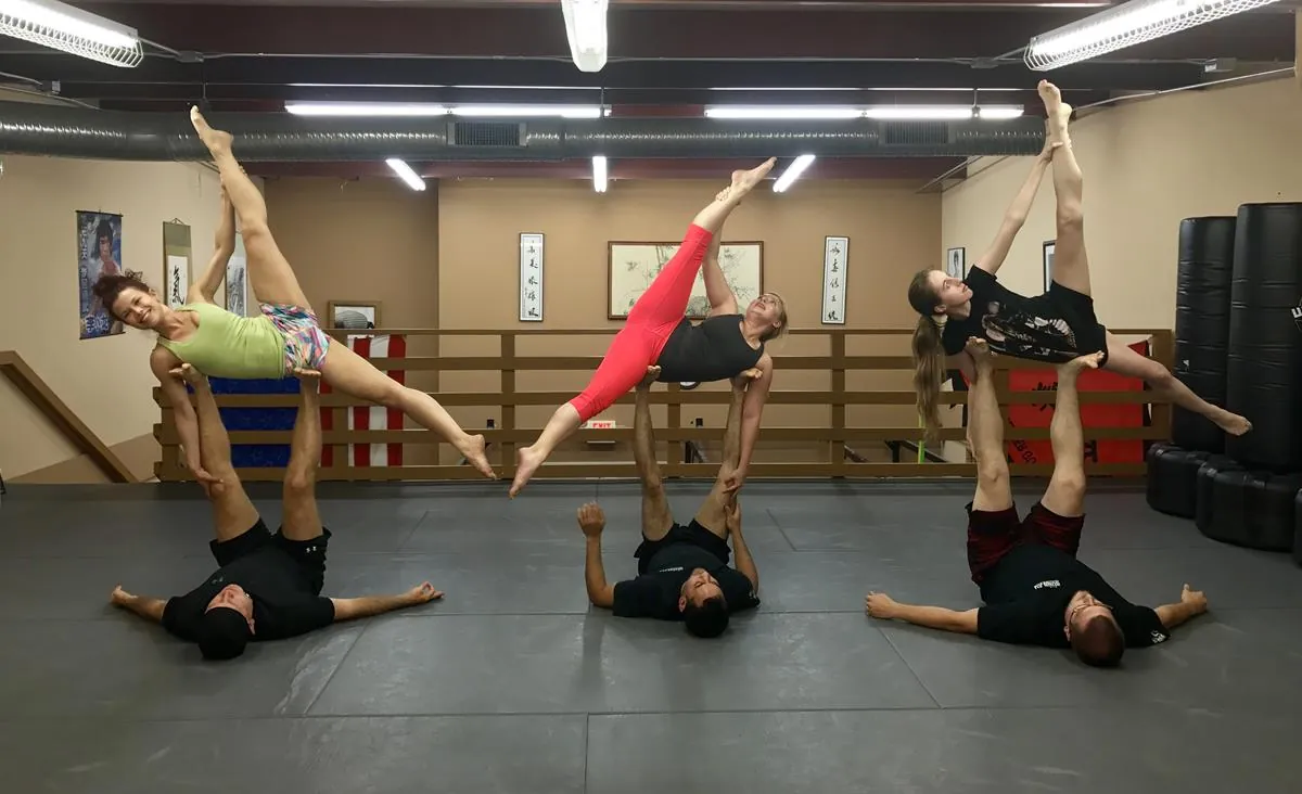 Three acro yoga pairs balancing on the studio mats